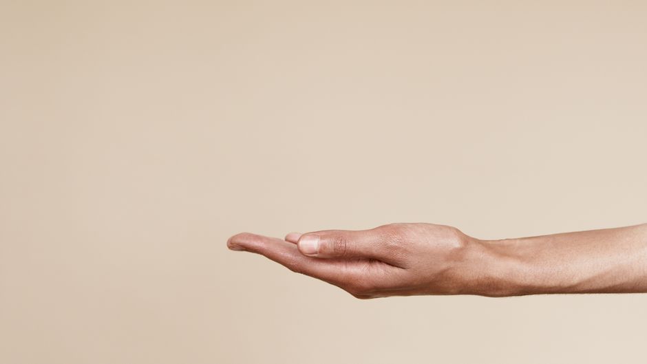 Close-up of an open hand reaching out isolated on a neutral background, symbolizing offering or receiving.