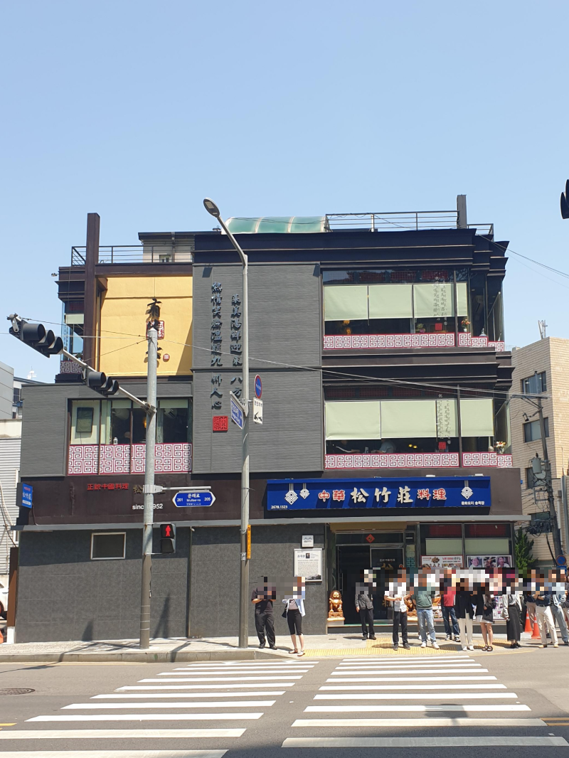 파란 하늘, 3층 송죽장 앞 횡단보도에 많은 사람들이 서 있다.