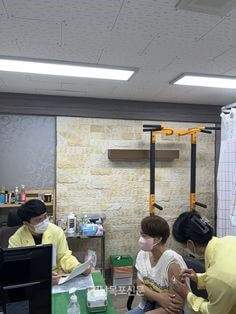 병원에서-상의를-올리고-노란-가운을-입은-간호사가-주사를-놔주는-모습