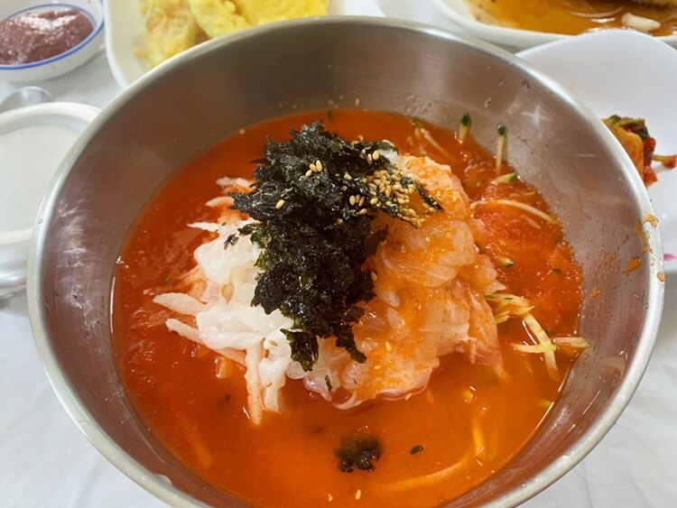 빨간 육수와 흰살생선회, 오이와 배, 김이 함께 담긴 물회 사진