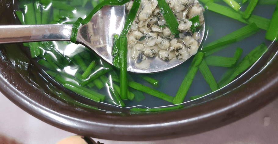 숙취해소에 좋은 음식 재첩 국을 수저를 뜨고 있다