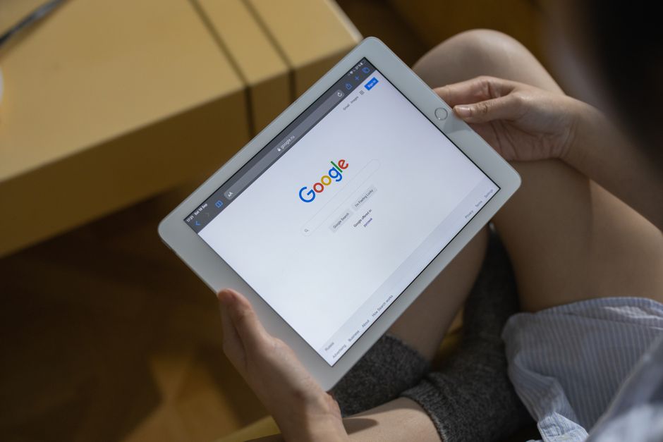 구글 검색 페이지를 보여주는 태블릿을 들고 있는 손의 클로즈업.