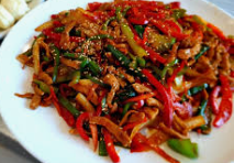 고기와 채소가 듬뿍 들어간 고추잡채가 하얀 접시에 담겨있다.