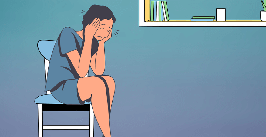 손으로 머리를 짚고 의자에 앉아 있는 여성