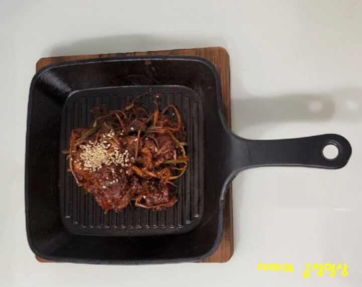 손잡이가 달린 주물 팬에 담긴 찜 갈비