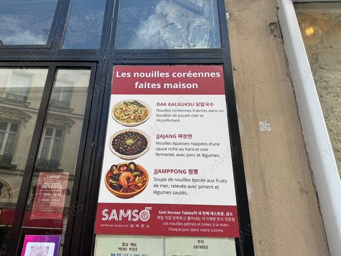 An outdoor signboard at SAMSO restaurant in Paris showcasing Korean noodle dishes made from scratch with French descriptions ❘ Un panneau extérieur chez SAMSO présentant des nouilles coréennes faites maiso