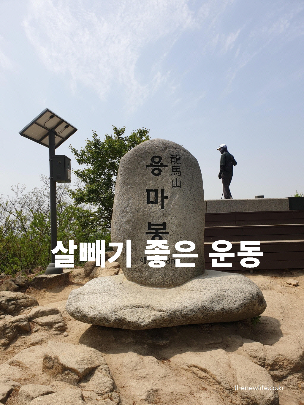 A large stone monument at the peak of Yongmabong (Yongma Mountain) under a clear blue sky, with a hiker standing nearby – a popular destination for those seeking good weight-loss exercise./맑은 하늘 아래 용마봉 정상의 큰 정상석과 등산객의 모습 – 살빼기 좋은 운동으로 인기 있는 장소.