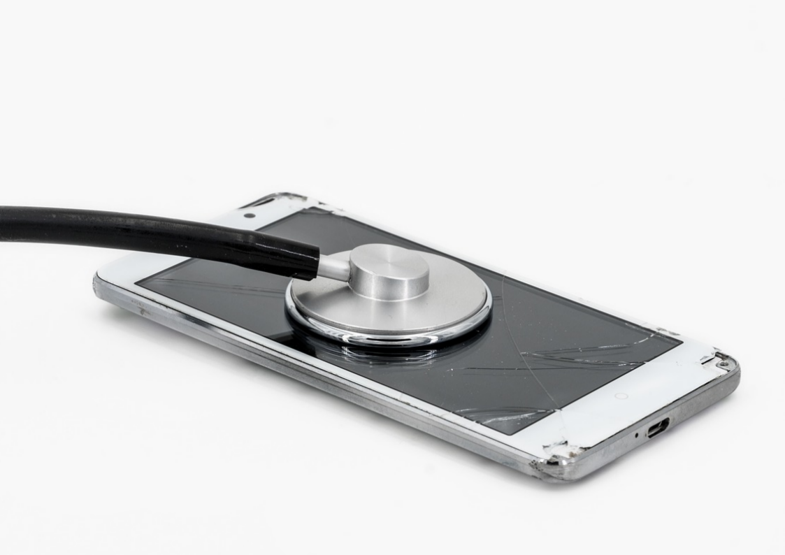 하얀-바닥에-놓인-파손된-휴대폰의-유리면에-청진기가-대어져-있다.