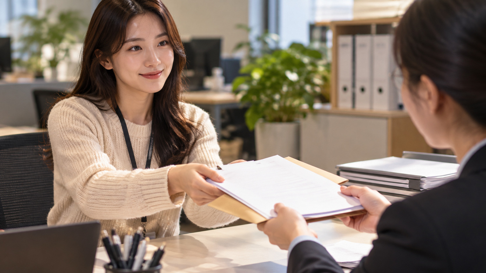 직장인이 연말정산용 종이 서류와 서류철을 회사 담당자에게 전달하는 실제 사무실 장면