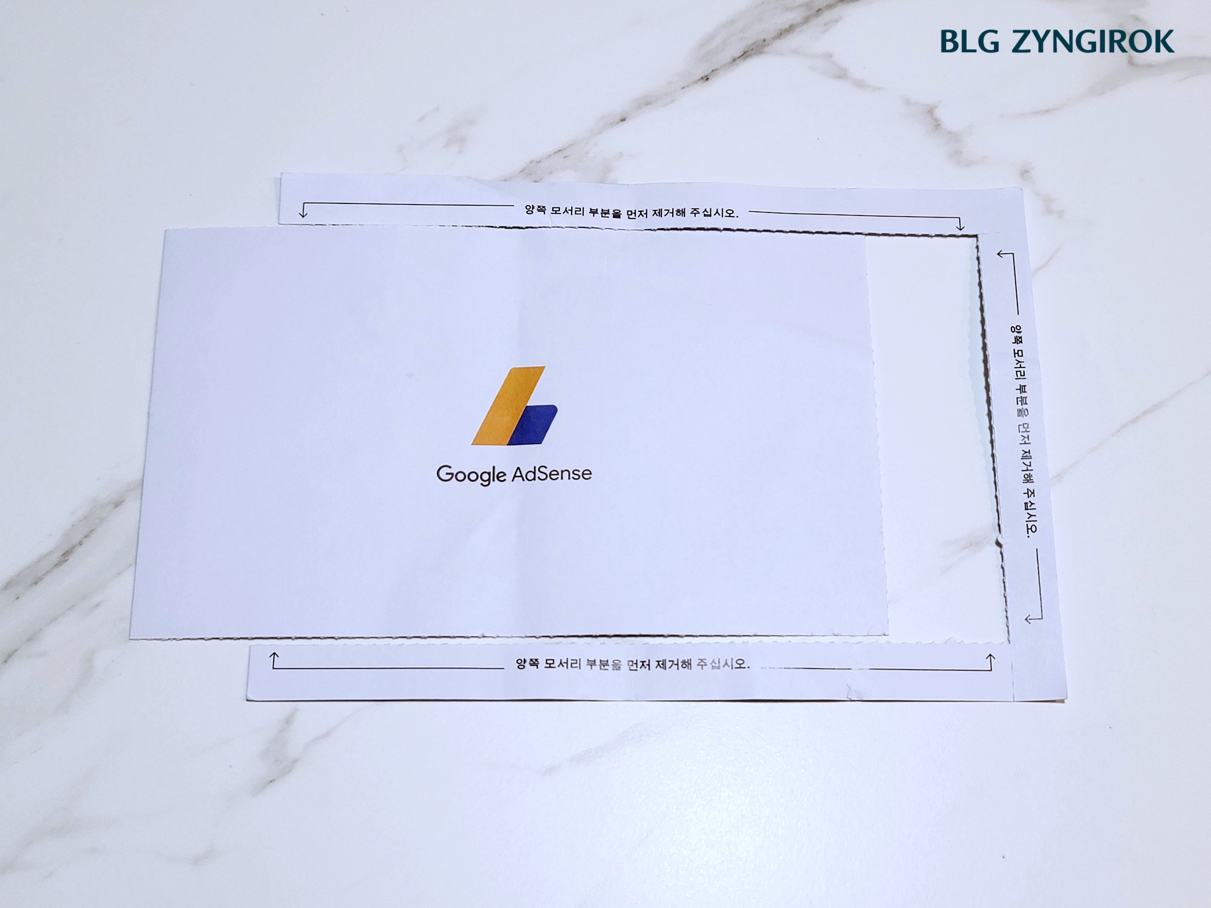 애드센스-엽서를-밀봉하고-있는-부위를-제거했다.