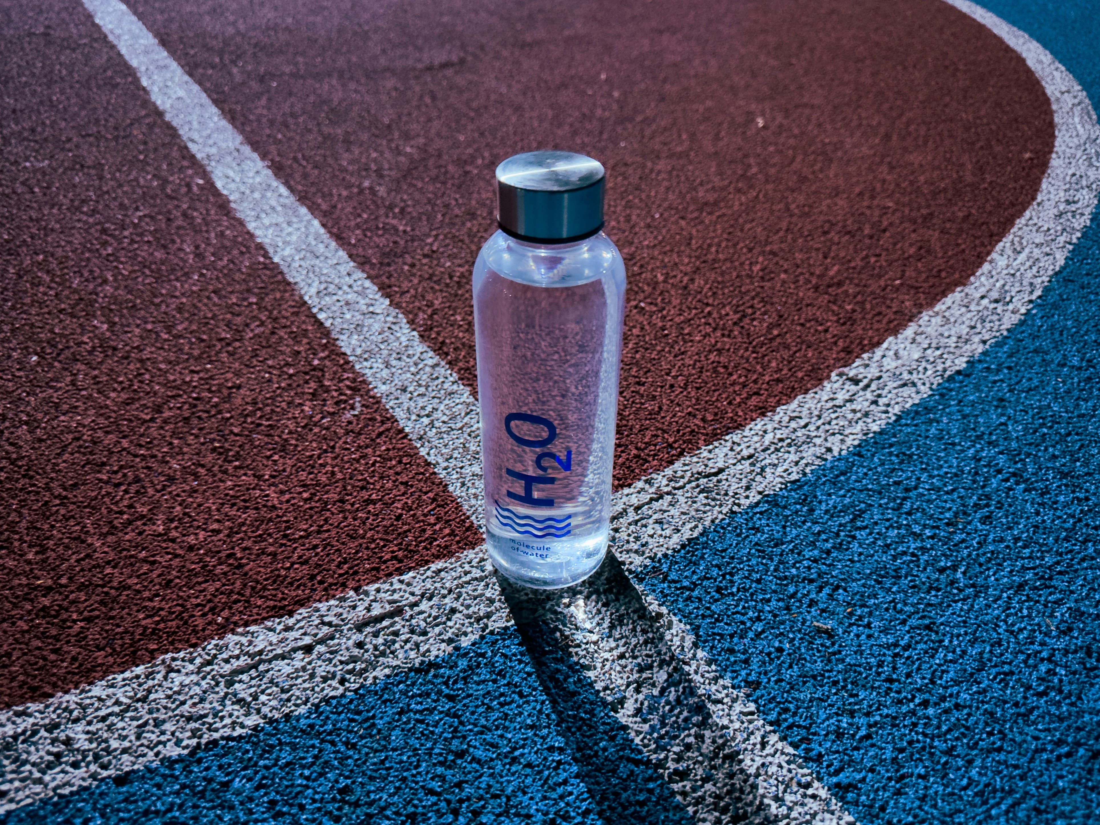"운동장 트랙 위에 놓인 물병, 여름철 장염과 어지럼증 예방을 위한 수분 보충의 중요성"