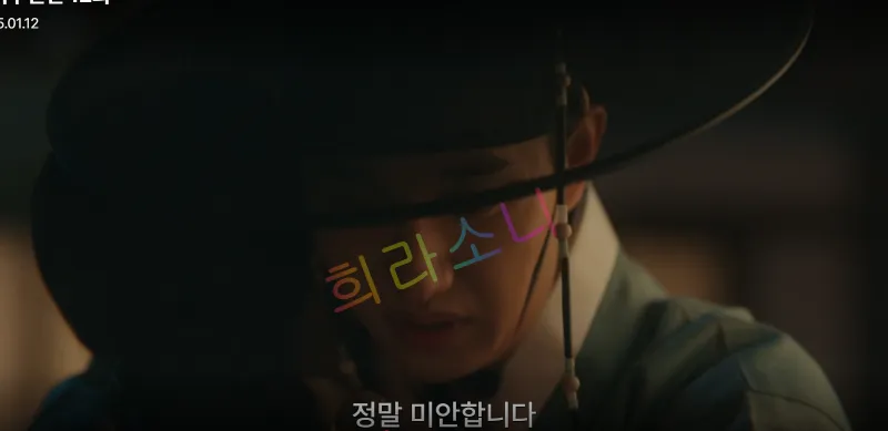 검은 갓을 쓴 도겸이 얼굴을 숙이며 어두운 표정을 짓고 있다. 화면에는 자막 