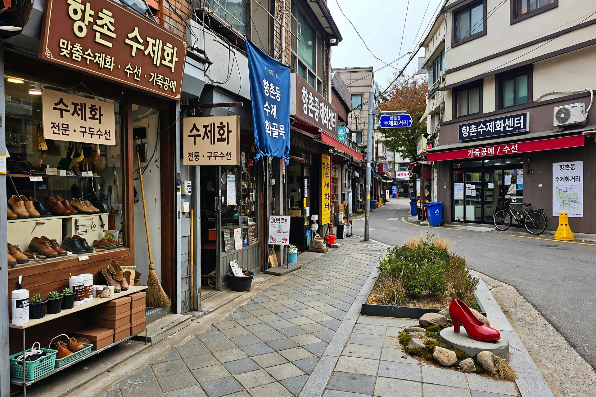 대구 중구 향촌동 수제화골목 골목길. 왼쪽에 수제화 가게와 진열된 구두, 오른쪽에 향촌수제화센터 건물과 파란색 수제화거리 이정표, 보도 화단 옆 작은 빨간 하이힐 조형물.