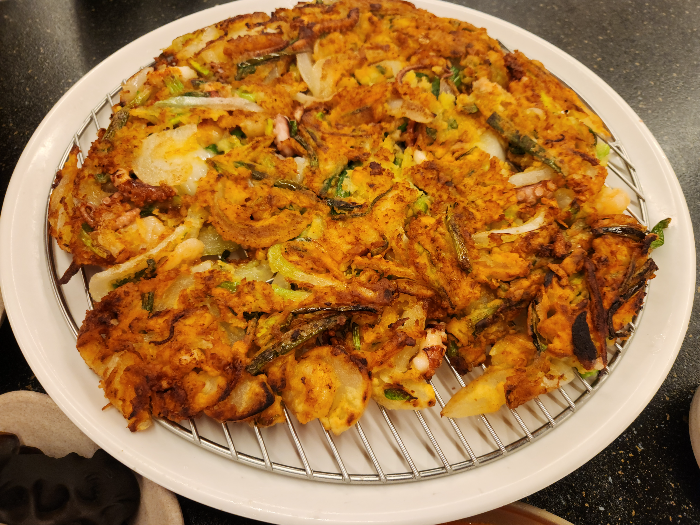 A plate of pajeon is on the table. チヂミ.