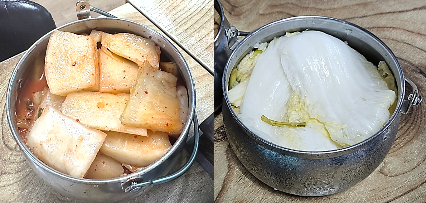 석박지와 백김치가 테이블마다 큰 스테인리스 반찬통에 담겨져 있는 모습