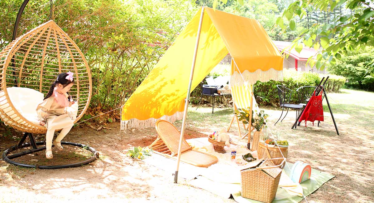 여자아이가 의자에 앉아 피크닉을 즐기고 있다.