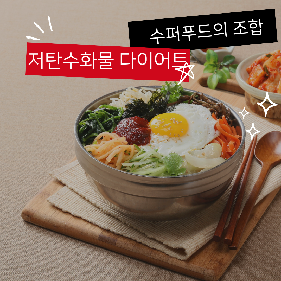 주황색, 초록색, 노란색의 야채가 곁들어진 맛있어 보이는 음식이 보울에 담겨있고, 옆에 빨간색 김치와 초록 허브가 향기롭게 놓여져 있다.