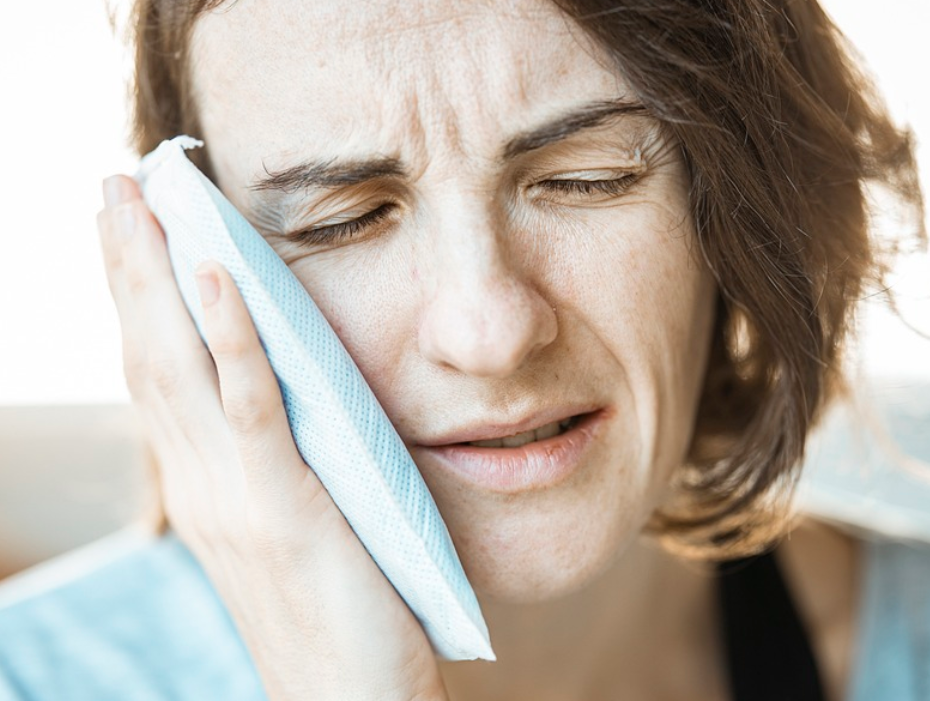 얼굴에 얼음 찜질을 하고 있는 여성