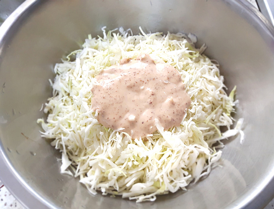 동그란 양은그릇에 양배추를 채를 썰어 놓은 것을 반쯤 담아두고 그 위에 참깨로 만든 드레싱을 뿌려 놓고 찍은 사진