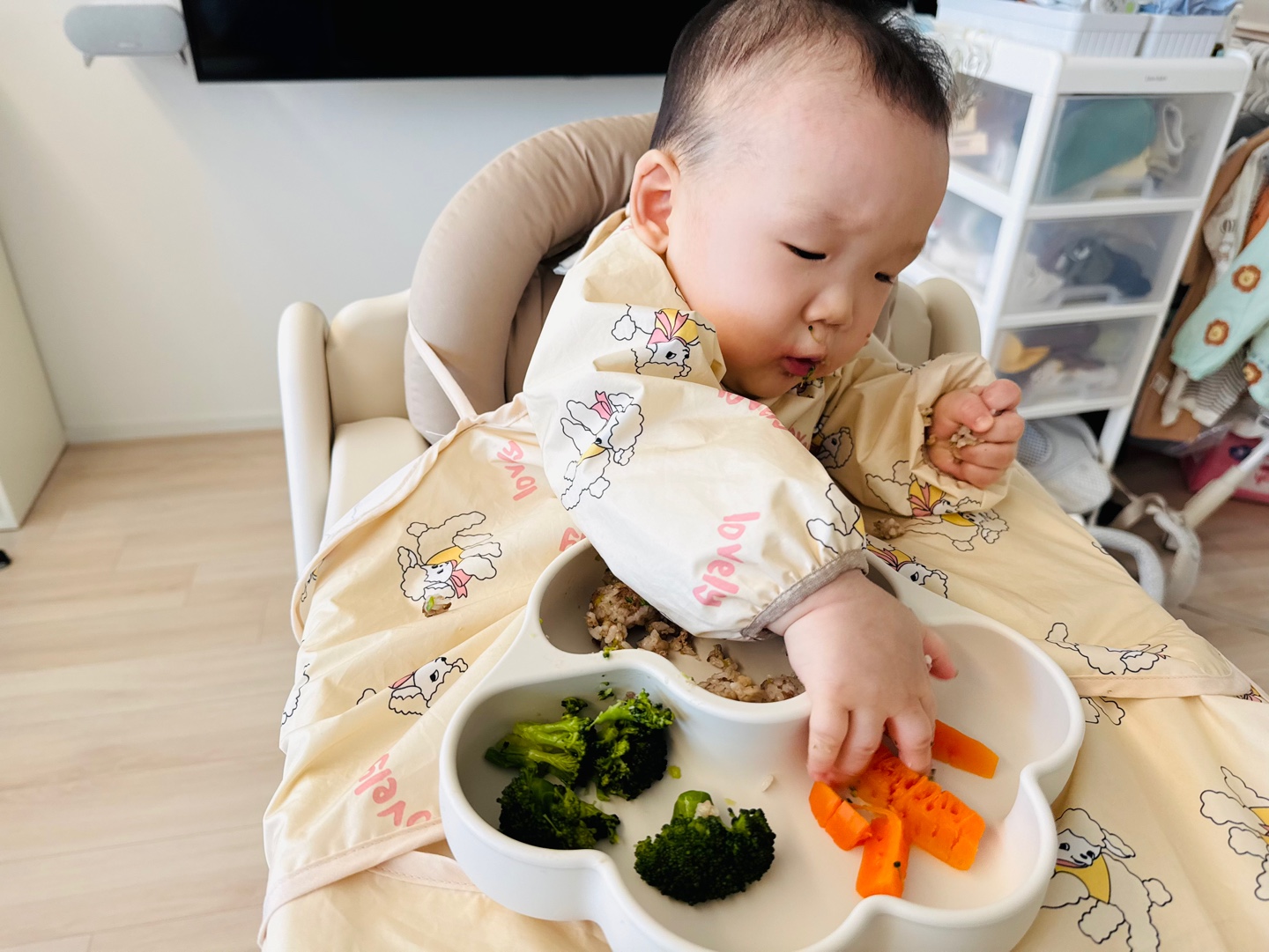 자기주도 이유식으로 브로콜리와 당근을 손으로 집어드는 9개월 아기 찬솔이