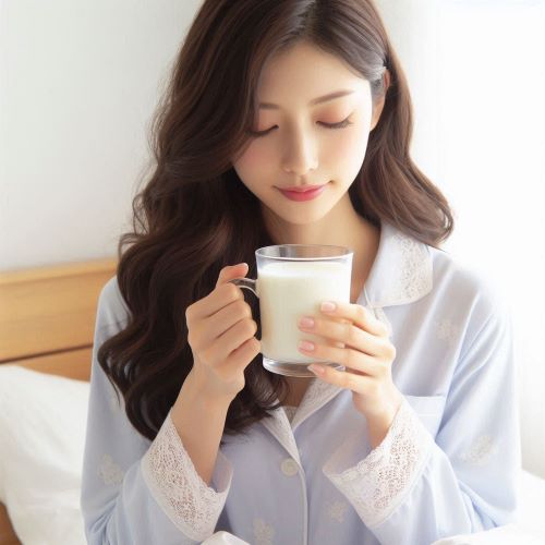 잠옷 차림의 여성이 따뜻한 우유를 마시고 있다.