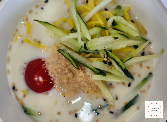 냉콩국수 완성-콩국수 면에 오이채와 방울토마토와 흑깨와 참깨를 넣은 콩국물을 부은 것