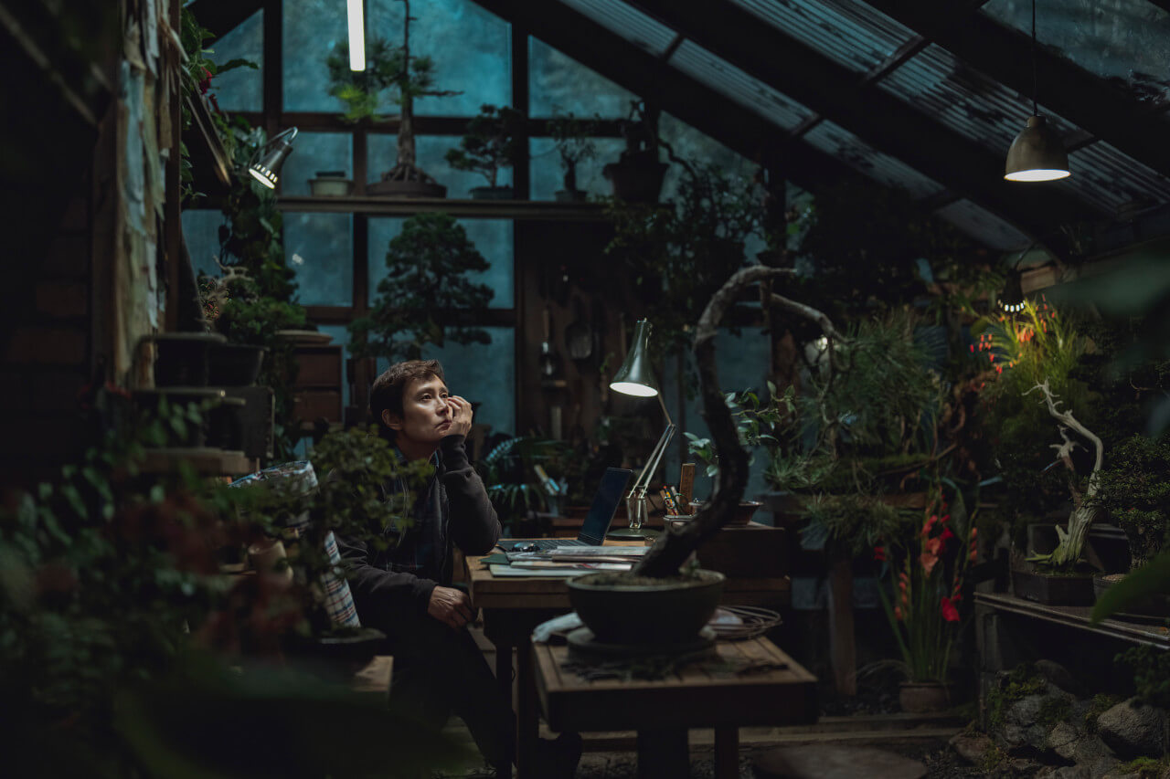 만수가 자신의 집 온실에서 고뇌에 빠진 모습