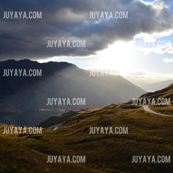 뉴질랜드 산악 지역의 일몰 풍경&amp;#44; 구불구불한 도로와 햇빛이 비치는 언덕.