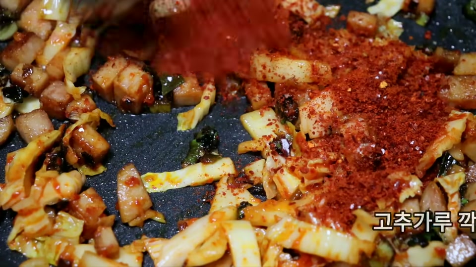 김치와 고춧가루를 넣고 볶는 장면