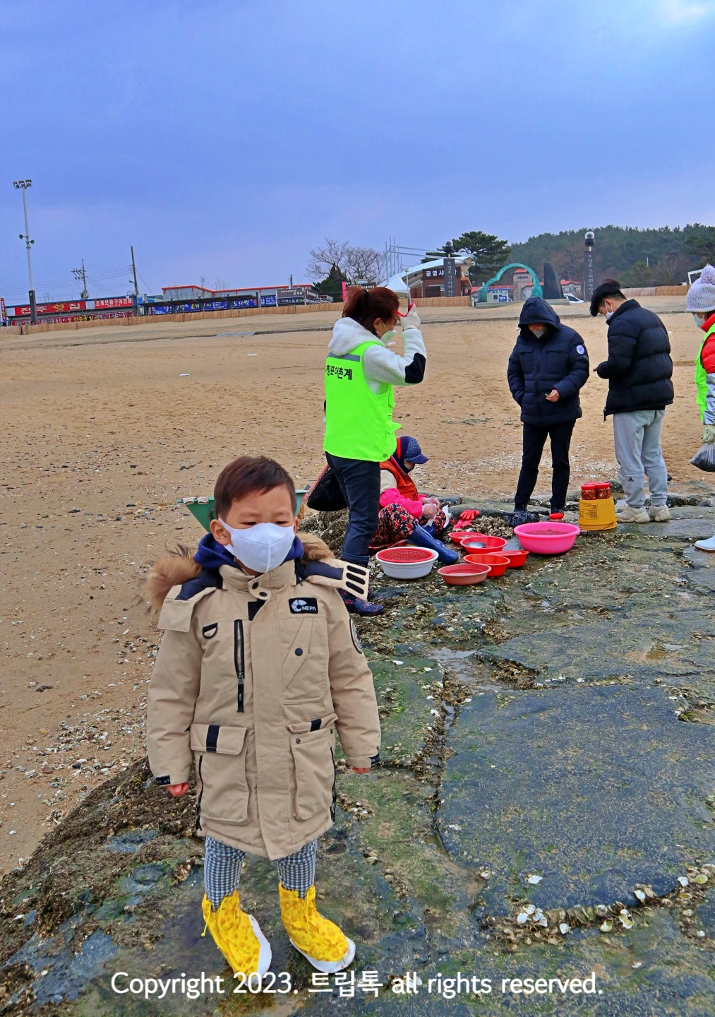바위위에 한 아이 뒤로 한 사람이 해산물을 팔고 있다