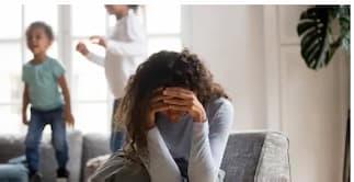 육아 스트레스로 지친 엄마가 소파에 앉아 머리를 감싸쥐고 있는 모습