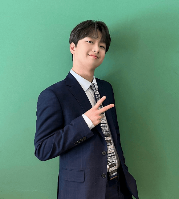 파란 수트를 입고 초록 배경 앞에서 사진 찍는 이찬원의 모습