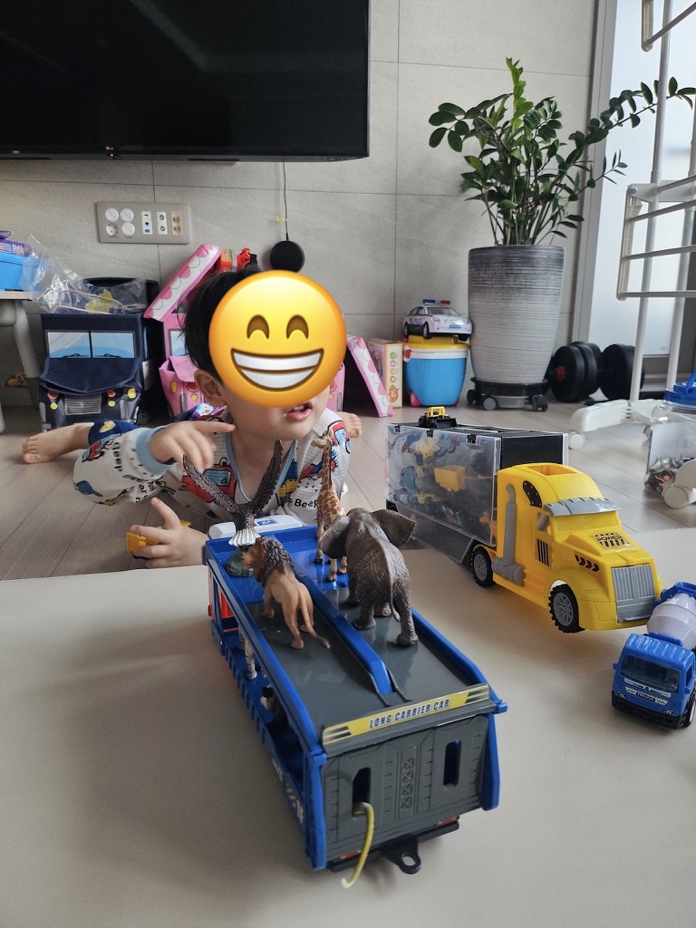 혼자 장난감 트럭과 동물들을 배치하며 노는 아이