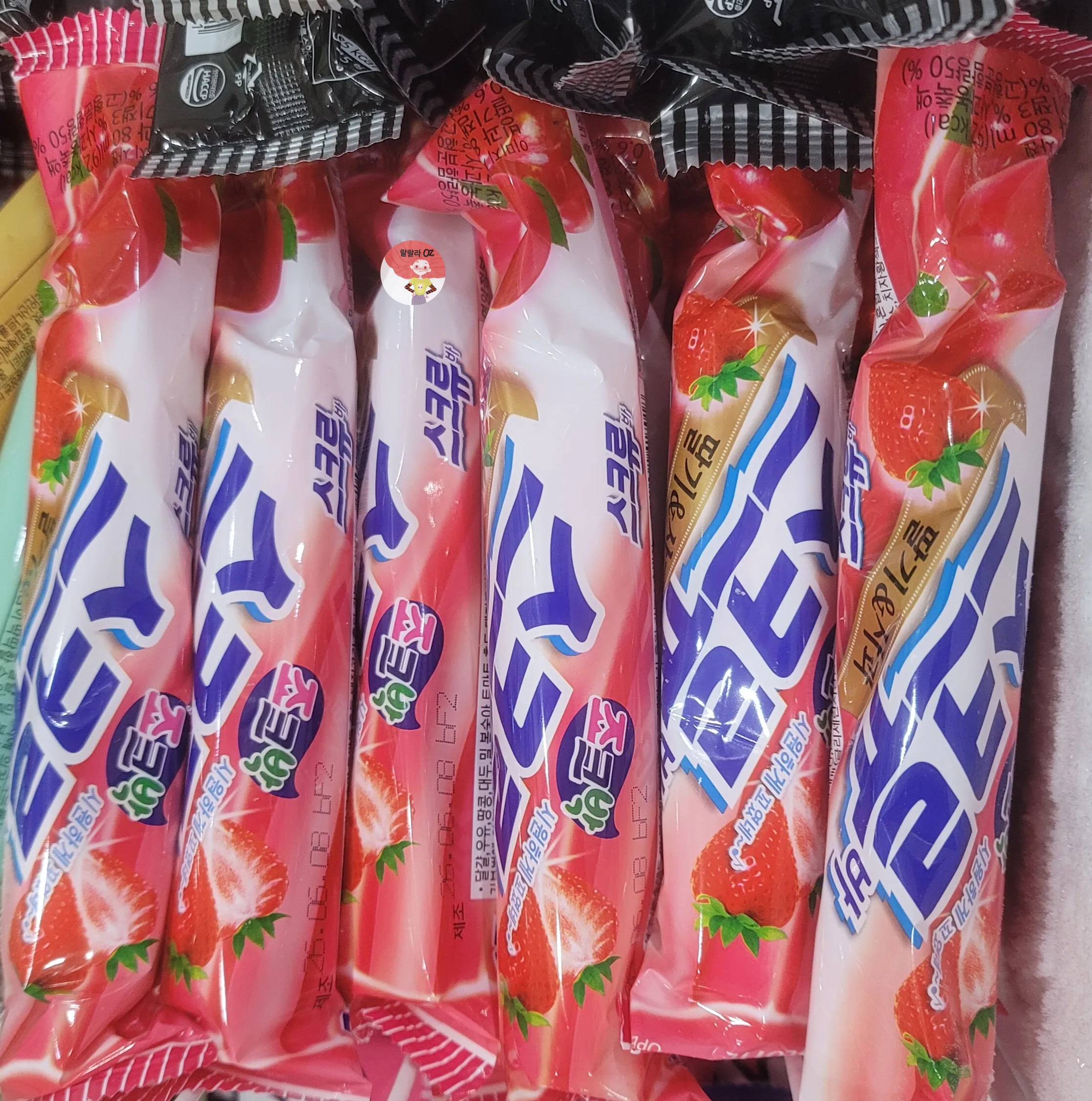 냉동 진열대에 진열된 롯데 스크류바 딸기·사과 믹스맛 포장지. 딸기와 사과 그림이 함께 인쇄된 분홍·초록색 디자인입니다
