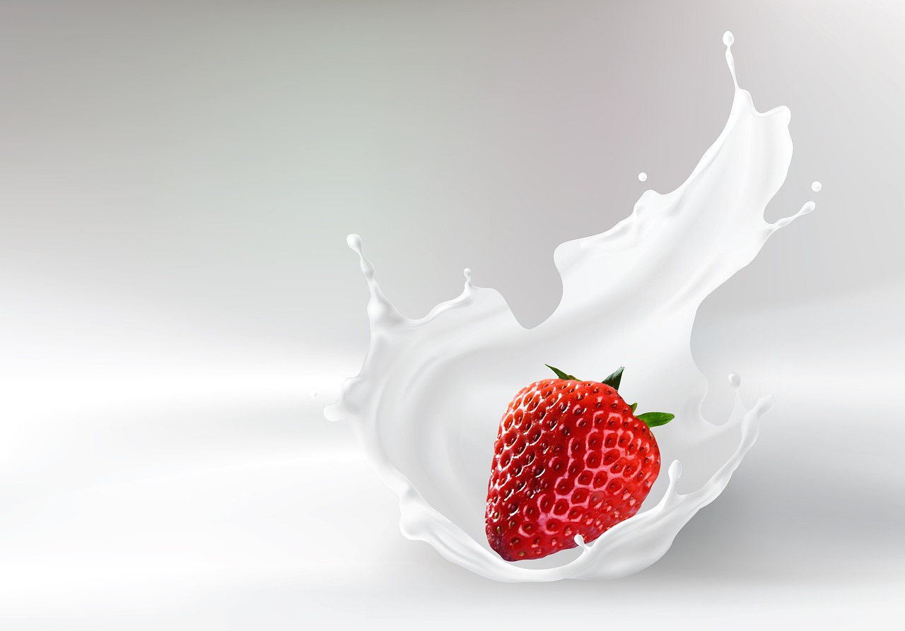 흰 우유에 빨간 딸기가 빠지는 순간으로 우유가 튕기고 있다.