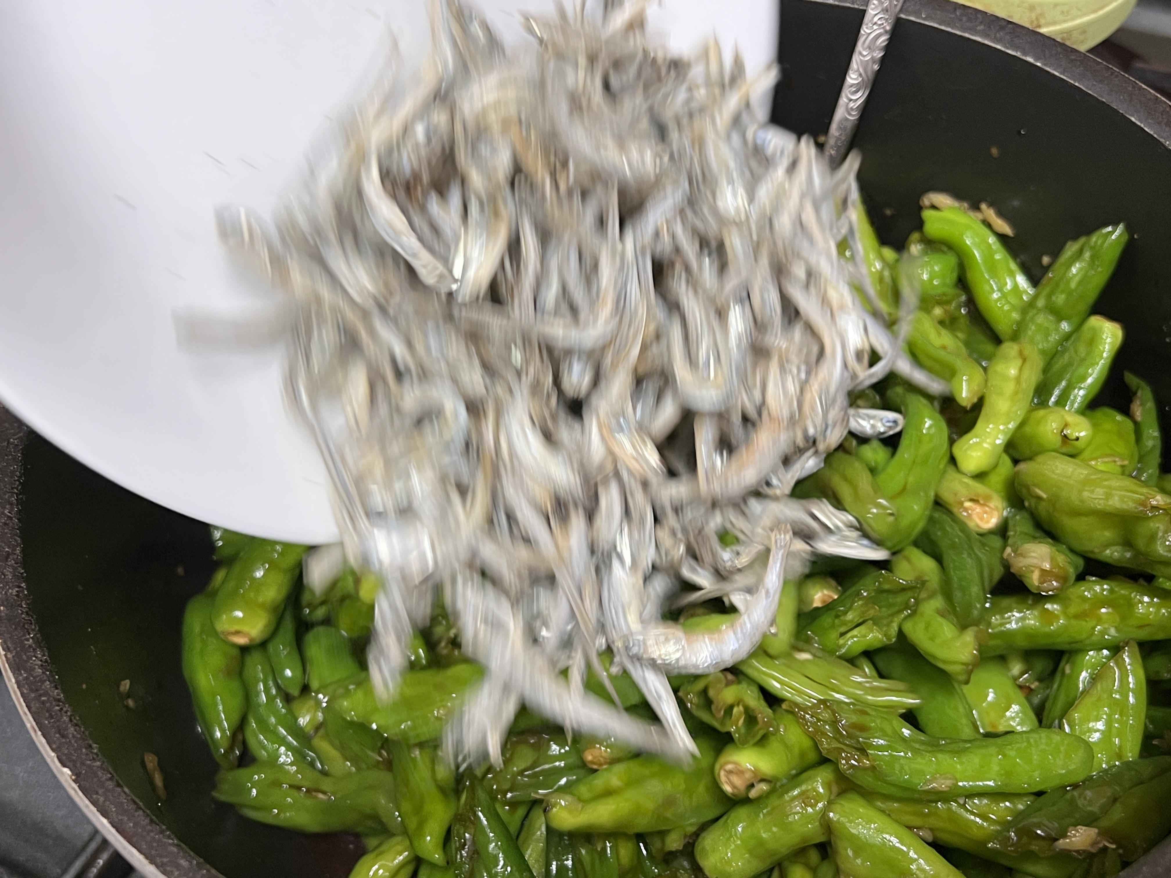 볶고 있는 꽈리고추에 덖어 놓은 멸치를 넣는 사진