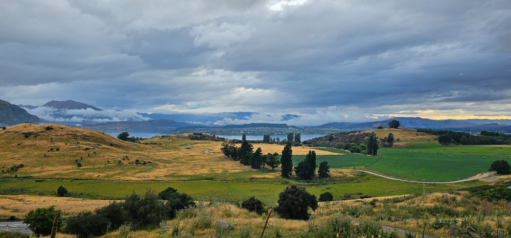 짙은 구름, 멀리에 보이는 호수, 앞에 펼쳐진 들판과 나무들