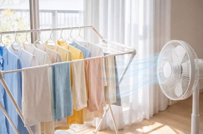 실내에서 빨래를 간격을 두고 널고 선풍기 바람으로 건조하는 장면