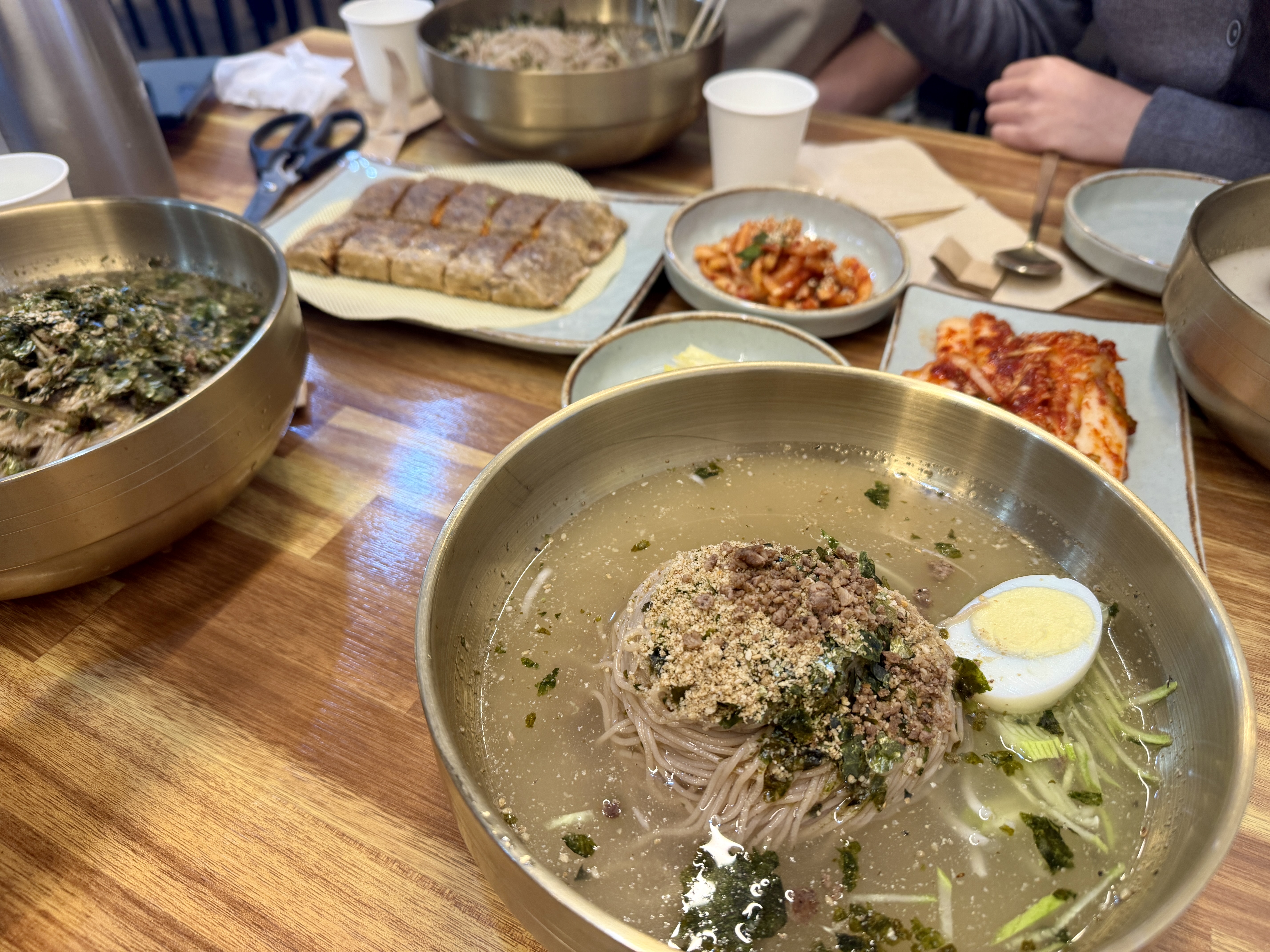 용인 금남막국수의 물막국수 한 그릇. 차가운 육수 위에 메밀면, 고기고명, 달걀, 김가루가 올려져 있고 반찬들이 함께 놓인 모습