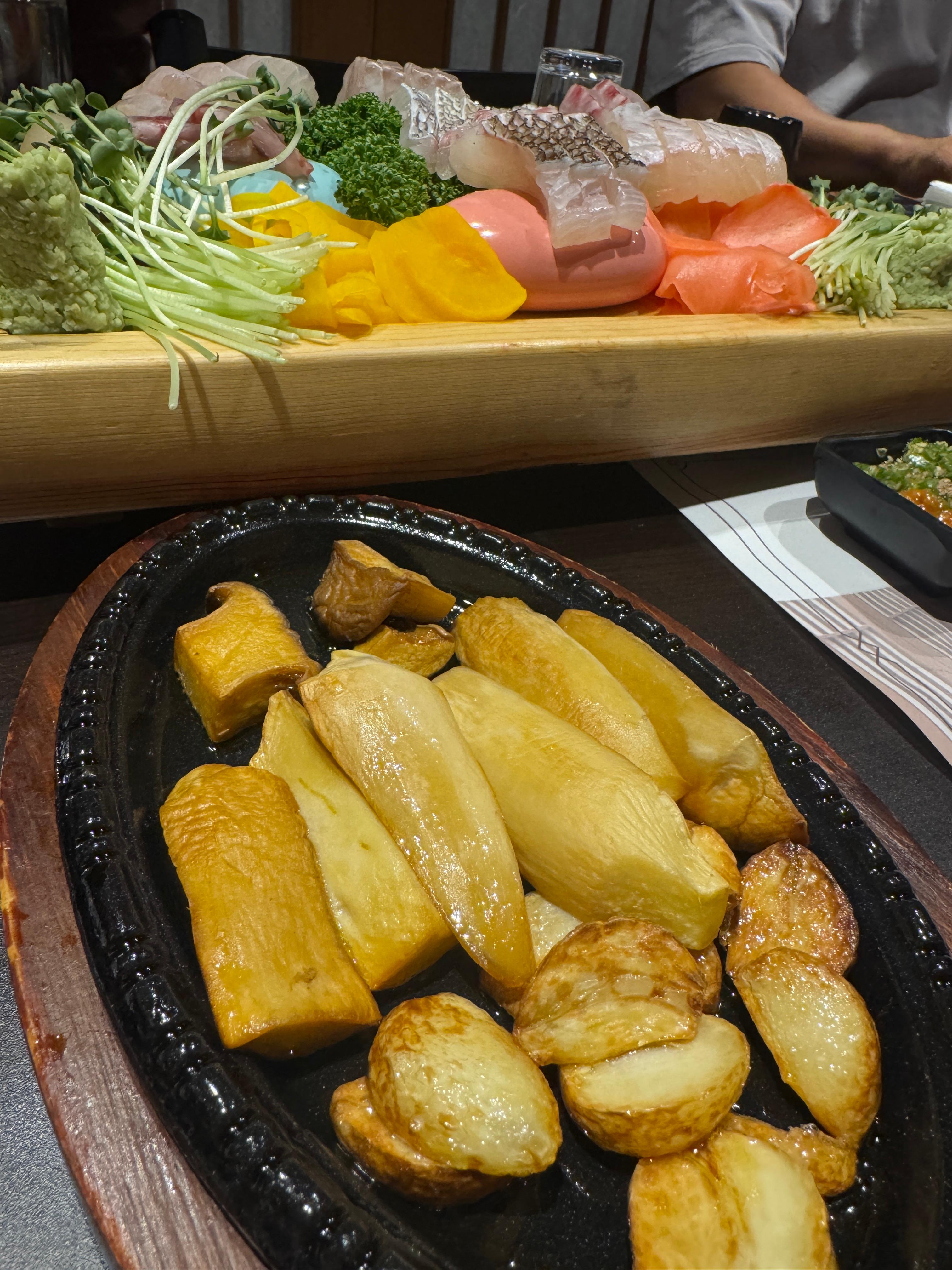 물고기 자리 논현점의 마늘버섯구이. 감자와 함께 뜨겁게 구워진 마늘버섯이 철판 위에 담겨 있다.