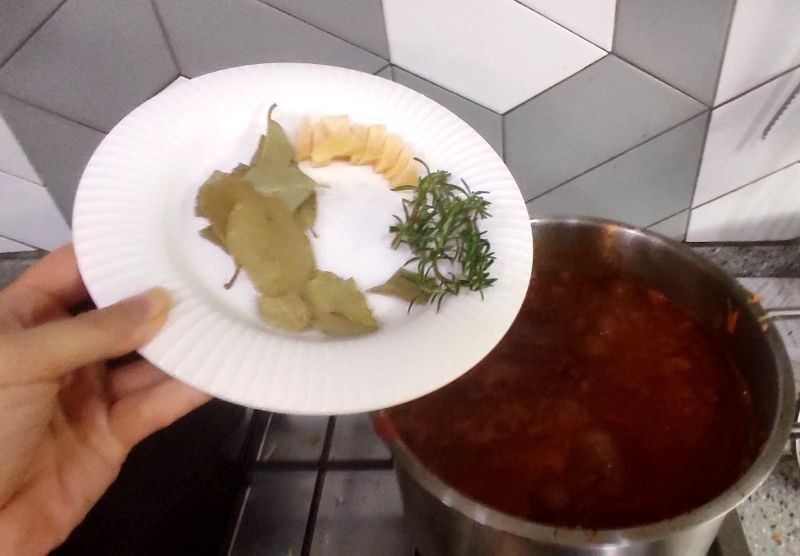 야채들과 고기 토마토 와인이들어간 큰 냄비에 월계수잎과 로즈마리 넣기