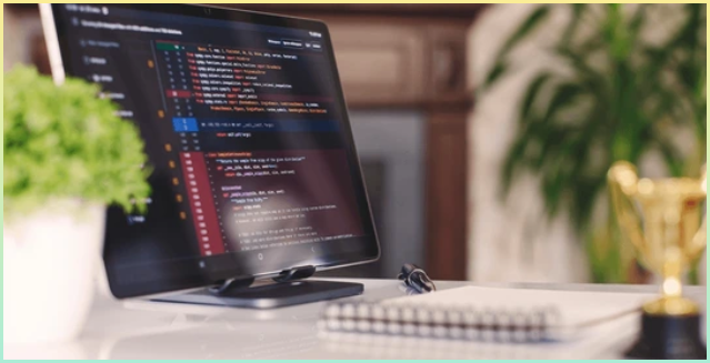 코딩을 하던 모니터 화면과 노트북과 화분이 있는 시각적 이미지