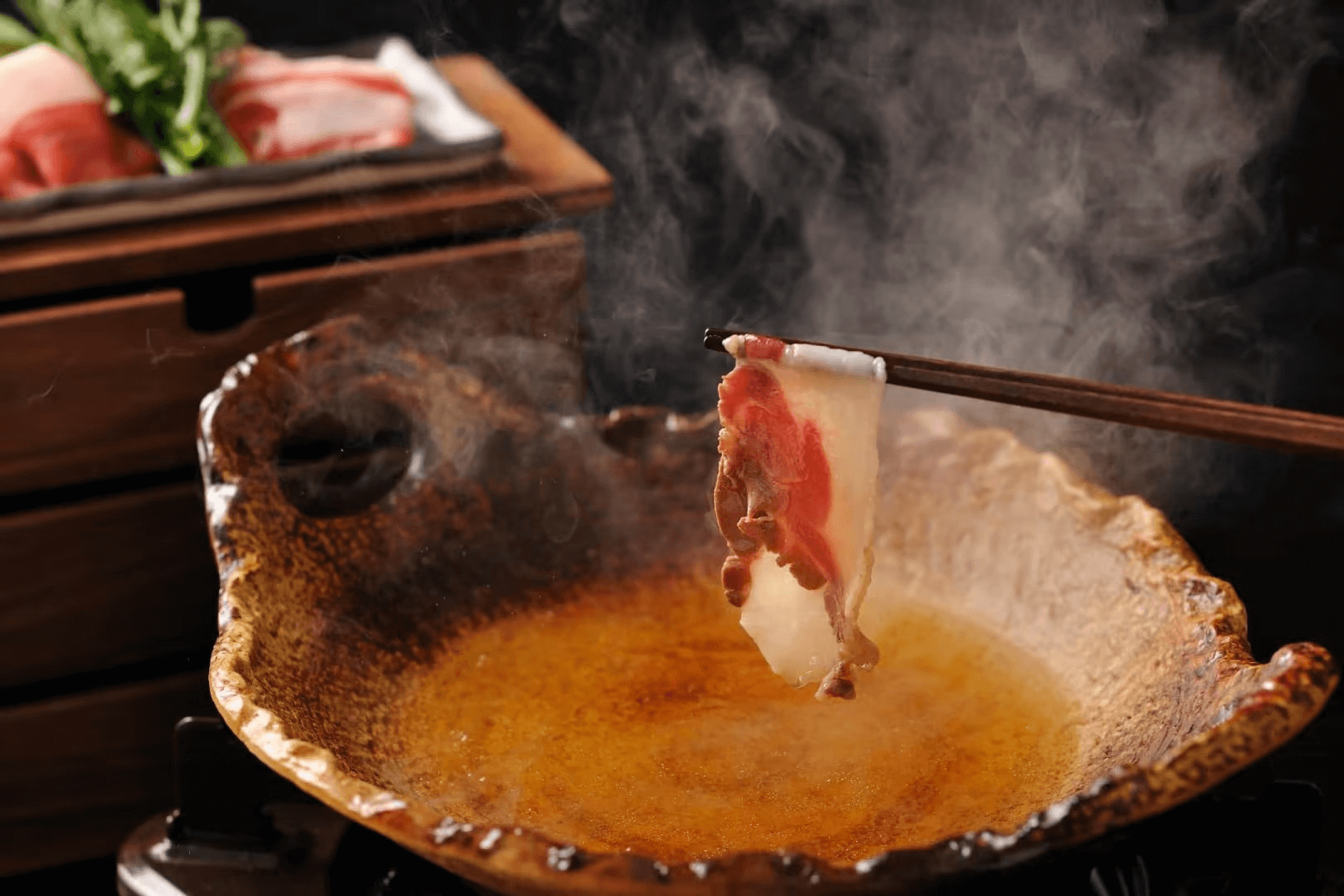 고급 전골 냄비에서 살짝 익혀지는 신선한 소고기 슬라이스, 향기로운 스팀이 올라오는 모습