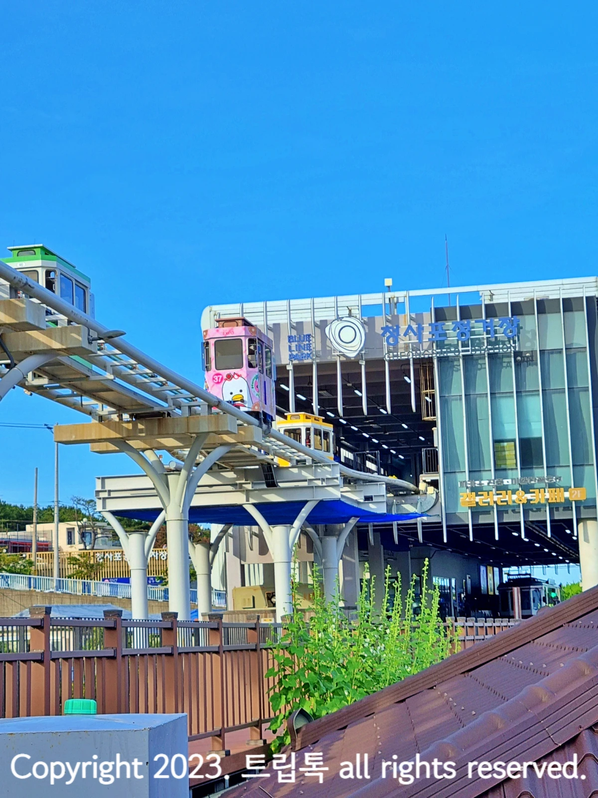 유리로된 건물이 뚫려서 레일이 있고 그 위로 직사각형의 분홍햇 스카이캡슐이 지나간다