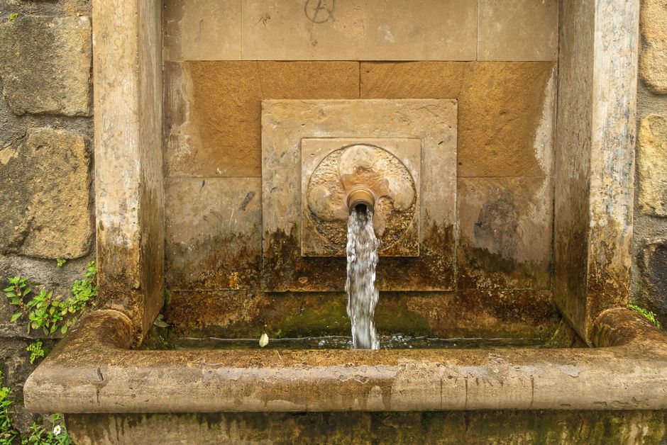 Rustic stone fountain pouring water, creating a vintage outdoor ambiance.