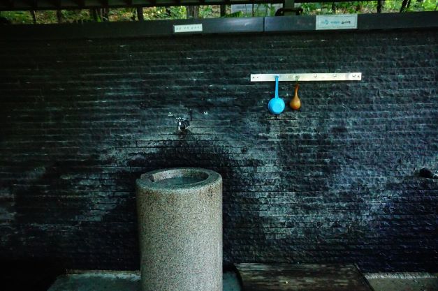 검은 벽돌벽, 우물 벽에 걸린 프라스틱 바가지, 하늘색 1, 누런 색 1, 수도꼭지 1,