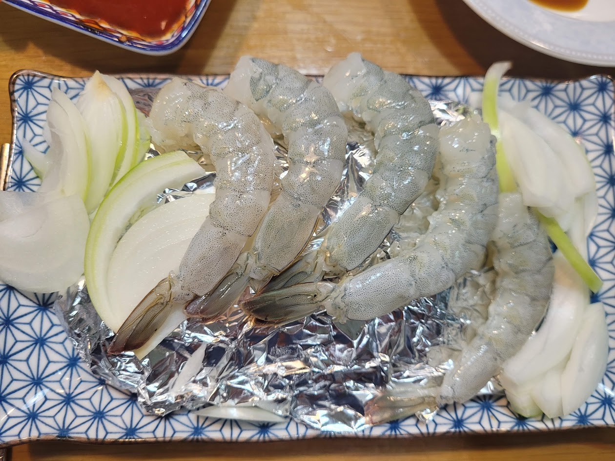 신선한 새우의 껍질을 벗긴 새우회를 양파와 함께 접시에 놓은 모습