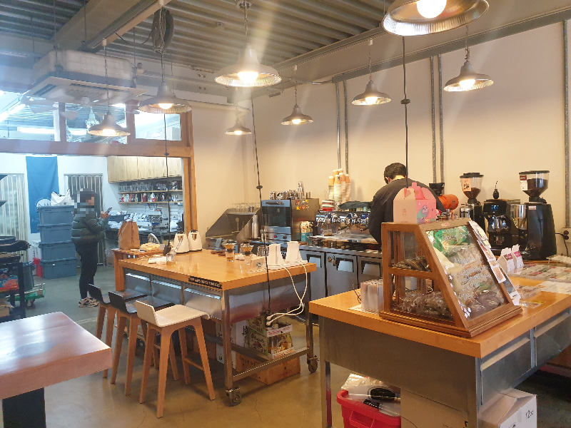 뒤편에 에스프레소 머신과 그라인더 그리고 드립 추출 도구들이 보인다.