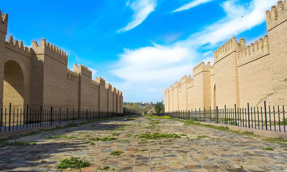 바빌론 유적지의 복원된 행렬 도로. 양 옆으로는 황토색 성벽이 길게 뻗어 있고, 돌로 포장된 도로가 의식의 중심 축 역할을 했던 장소임.