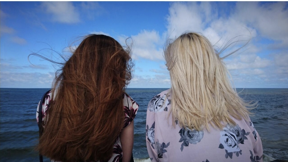 바다에서 여자 두 명의 뒷 모습이 보인다.